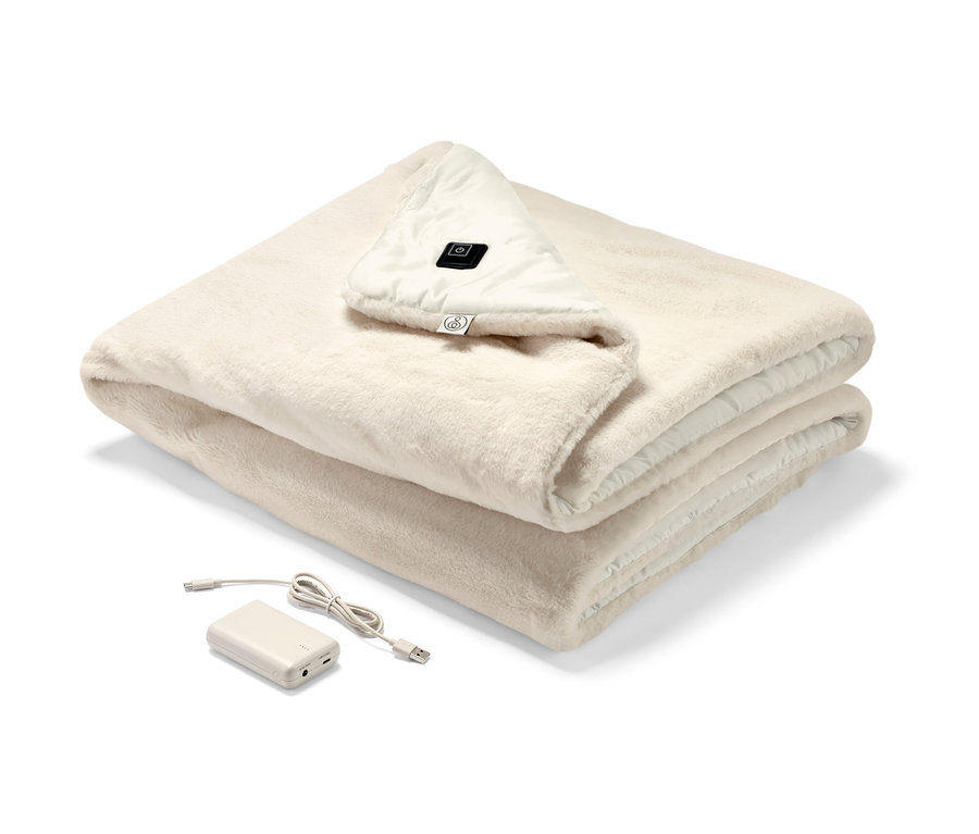 Egy összehajtott krémszínű elektromos melegítőponcsó akkumulátorral, látható kezelőpanellel.