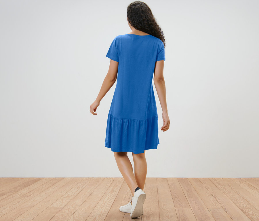 Egy nő hátulról, kobaltkék, fodros jerseyruhában.