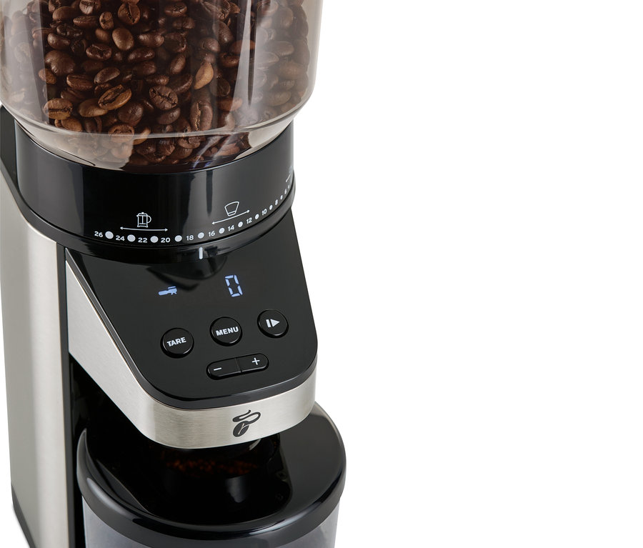 Egy elektromos kávédaráló részlete mérleggel, felül kávébabokkal.