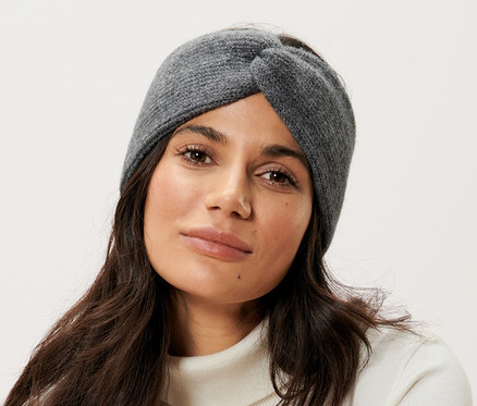 Egy nő ül egy széken, és szürke gyapjú fejpántot visel.