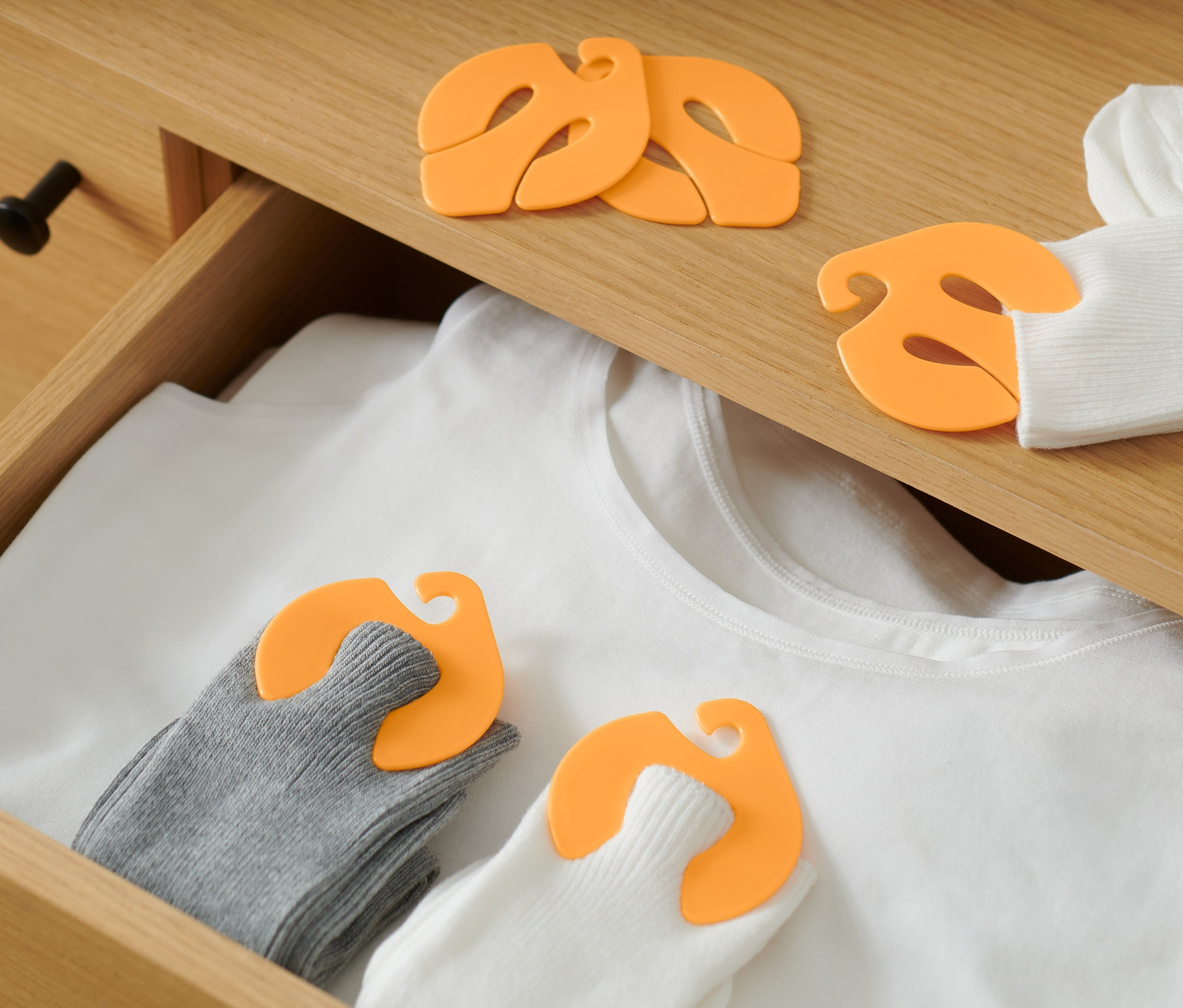 A fiókban egy fehér póló és zoknik találhatók, melyeket 20 zoknipárosító csipesz tart össze.