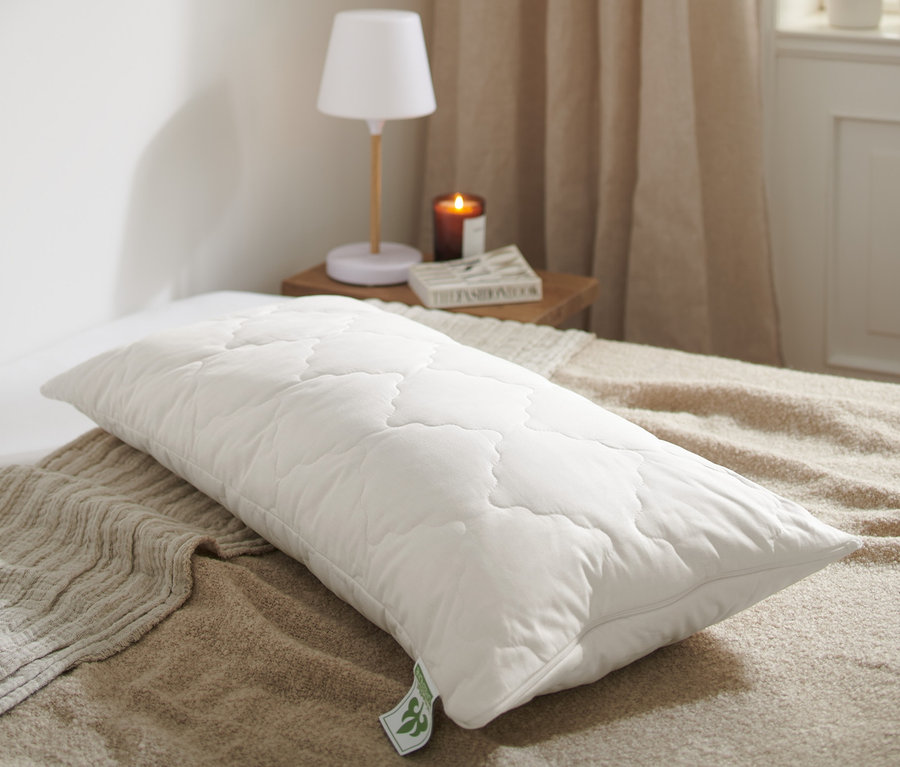 Egy steppelt, fehér irisette® greenline levendulás párna, kb. 80 x 40 cm méretben egy ágyon.