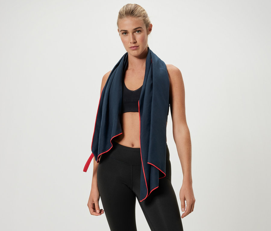 Egy szőke nő sporttörülközőt visel piros szegéllyel a nyakában.