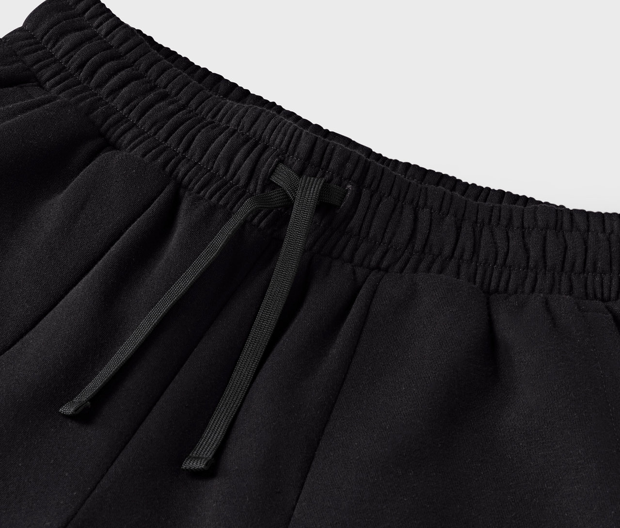 Egy fekete melegítőalsó részlete, húzózsinórral a derékrészen.