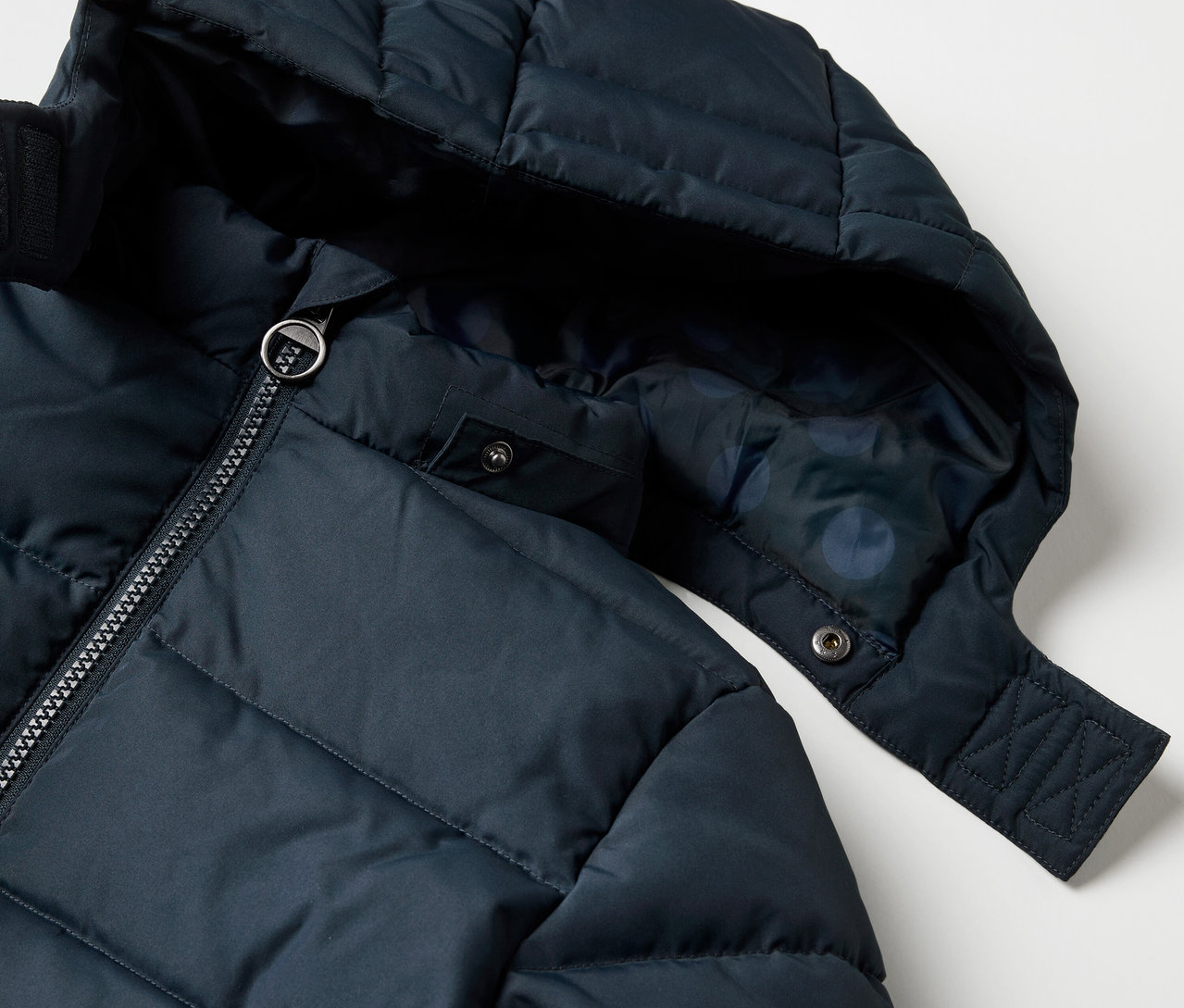 Egy gyermek termokabát részletes nézete kapucnival és cipzárral.