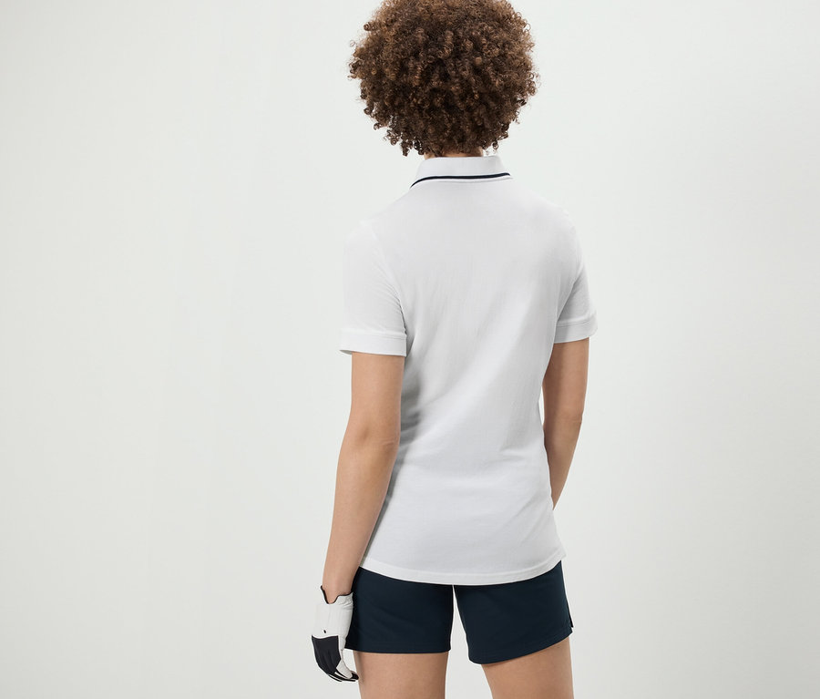 Hátulnézet egy göndör hajú nőről, aki fehér funkcionális pólóinget visel.