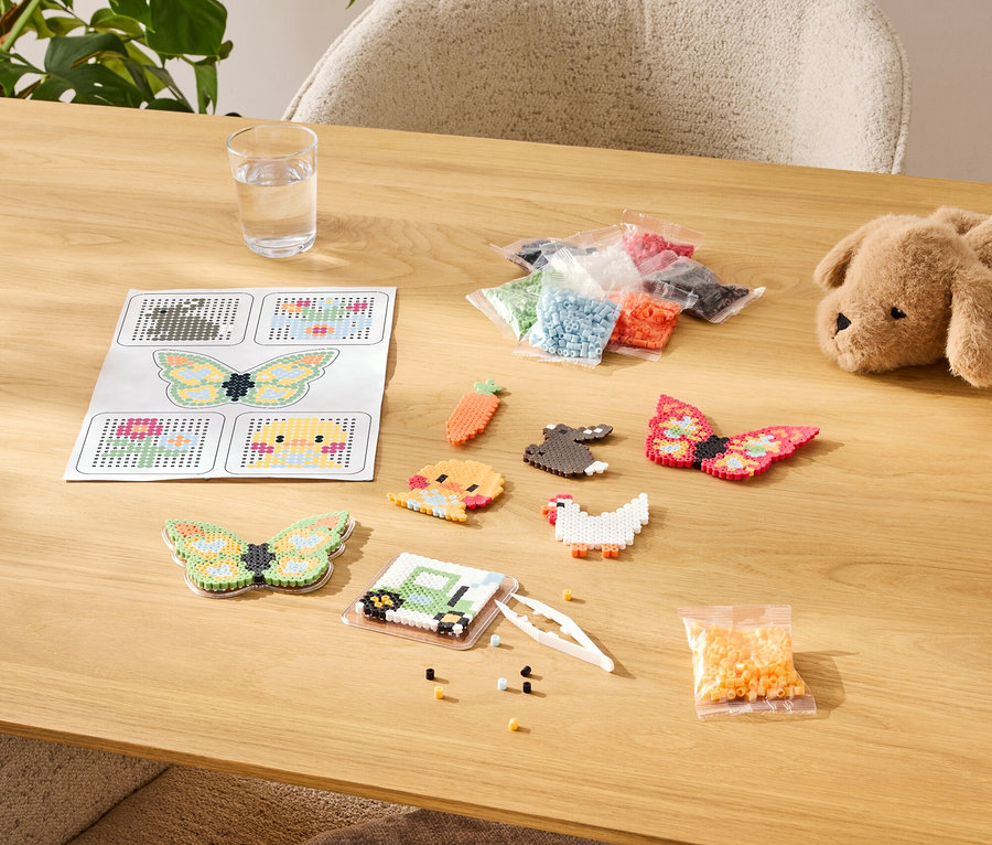 Asztal gyöngyvasaló készlettel, beleértve a sablonokat, a kész mintákat és a színek választékát zacskókban.