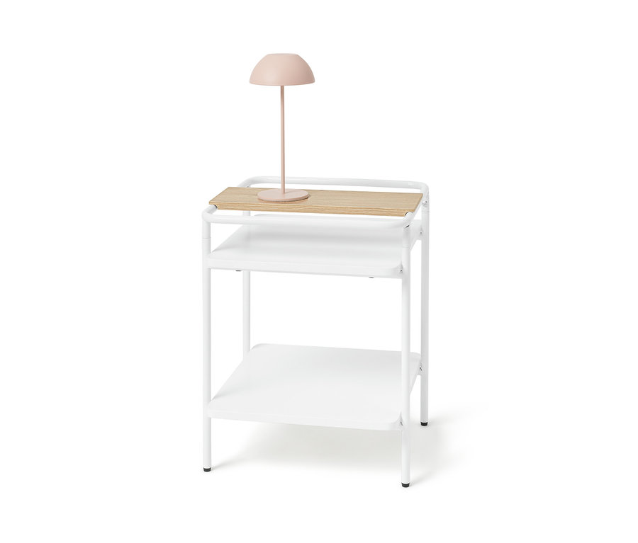 Fehér éjjeliszekrény világos fa felülettel és rózsaszín lámpával.