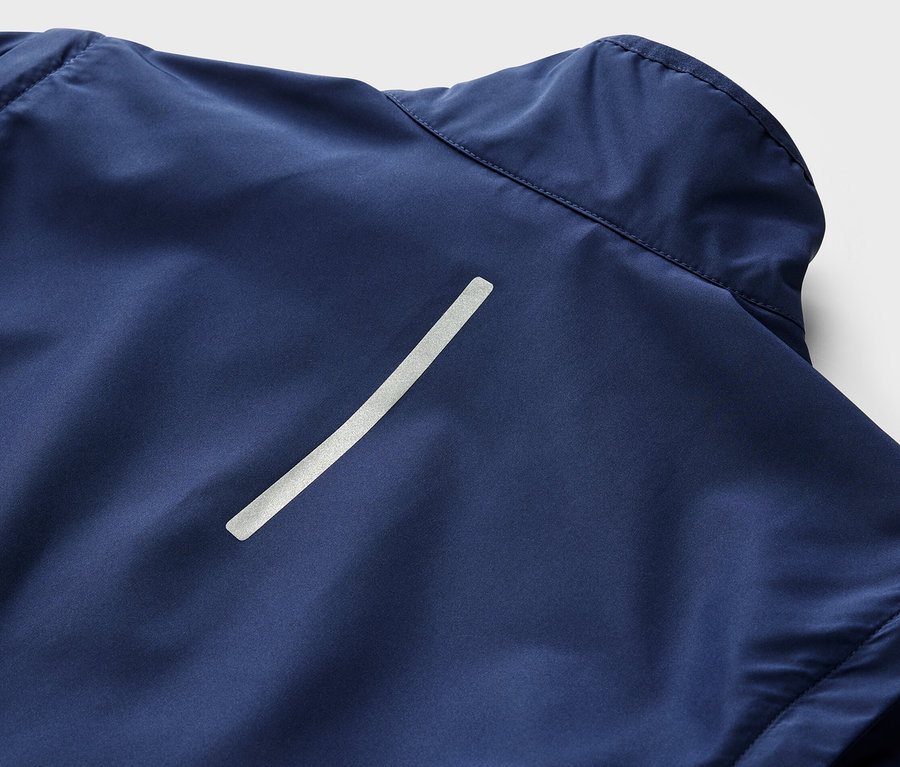 Egy sötétkék, 2 az 1-ben kerékpáros kabát részlete, fényvisszaverő csíkkal.