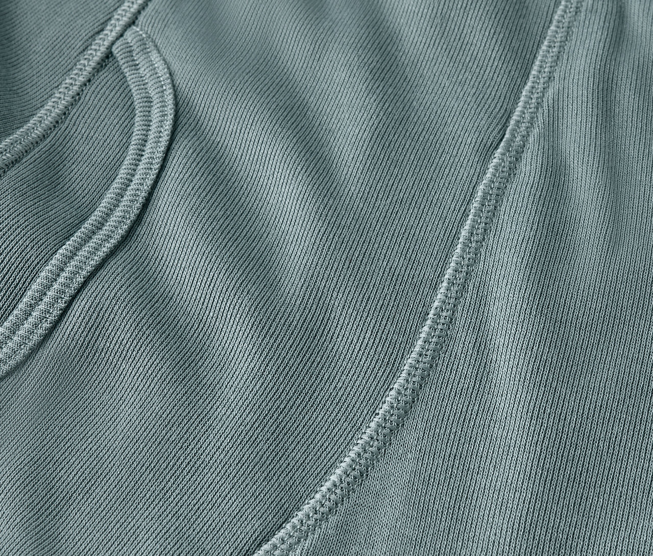 Egy kékeszöld szövet részlete zsebbel és varrással.