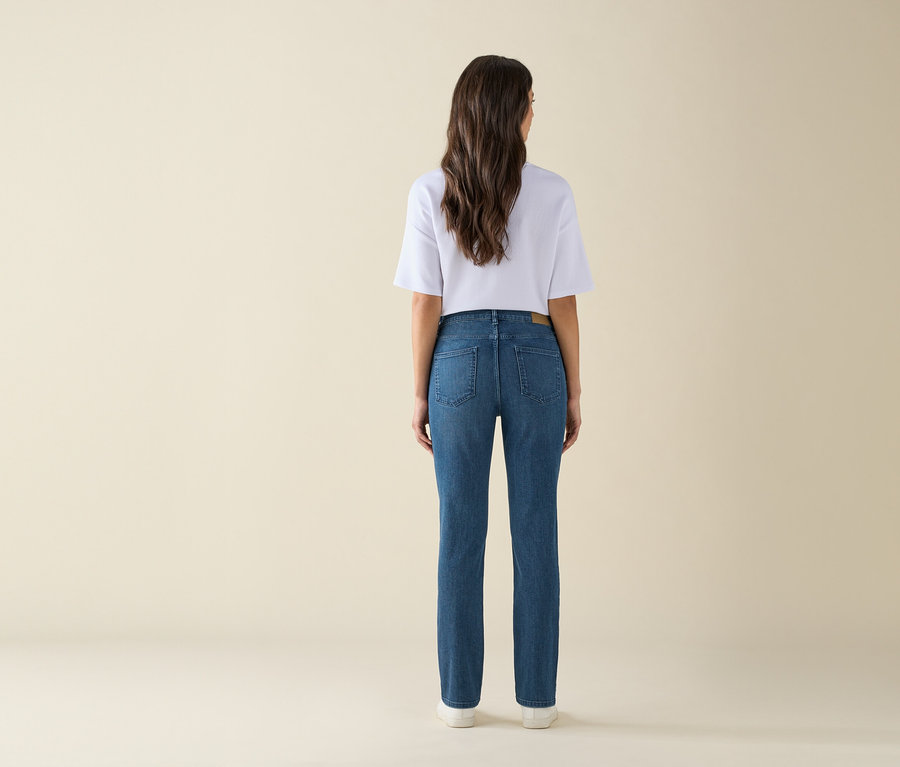Hátulról látható egy nő kék farmerben és fehér pólóban.