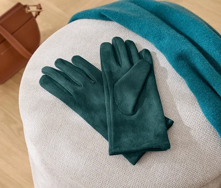 Egy fehér széken zöld kesztyűk, egy kék sál és egy barna kézitáska fekszik.