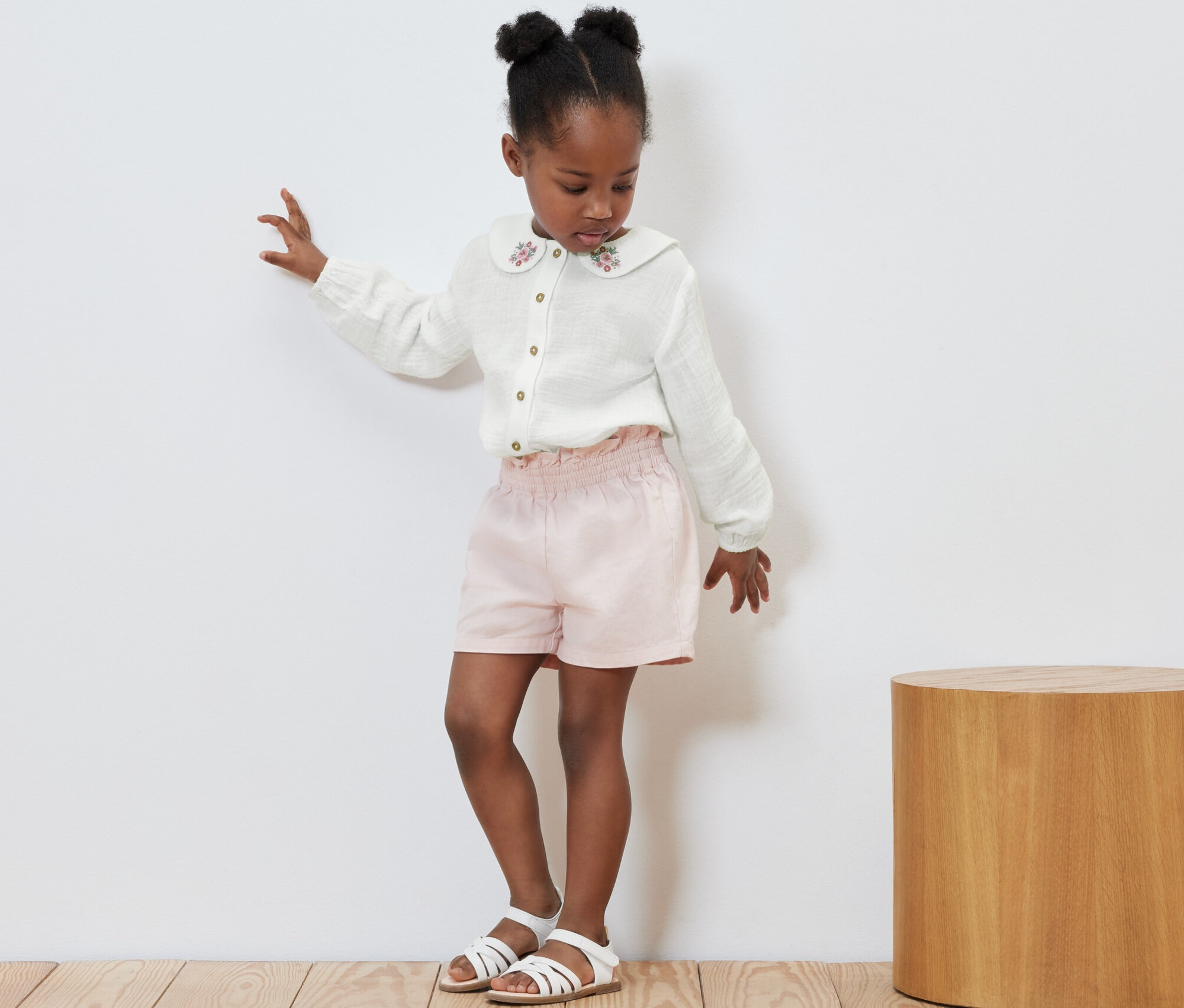 Lány táncol muszlinblúzban, rózsaszín rövidnadrágban és szandálban.