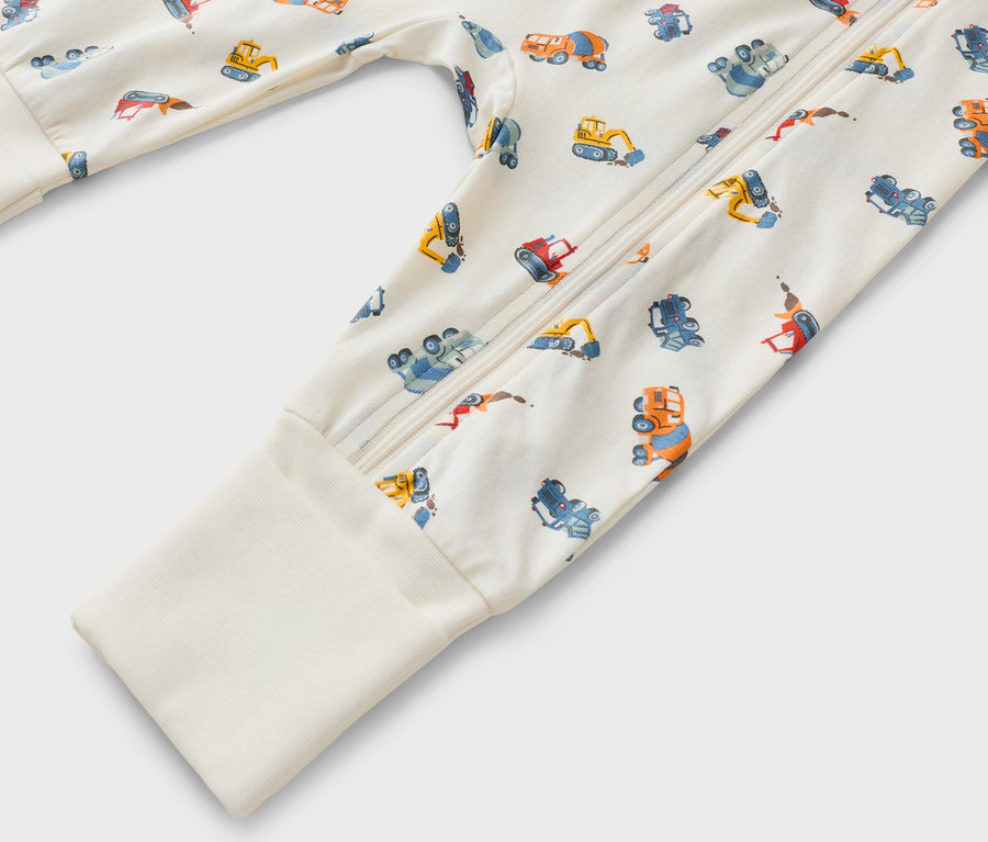 Közelkép egy hosszú ujjú, cipzáras, építőipari jármű mintás rugdalózóról.