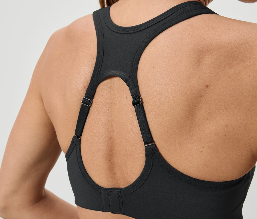 Közeli kép egy fekete sportmelltartót viselő nő hátáról, állítható pántokkal.