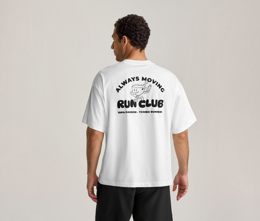 Férfi hátulról, fehér sportfelsőben, fekete "ALWAYS MOVING RUN CLUB" felirattal és futó kávéscsésze rajzzal.