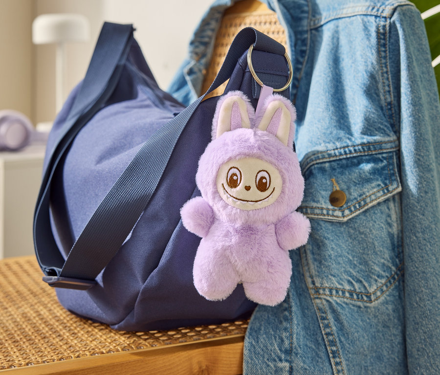 Egy kék táska a »Tchibobo« kulcstartóval egy farmerdzsekin lóg.