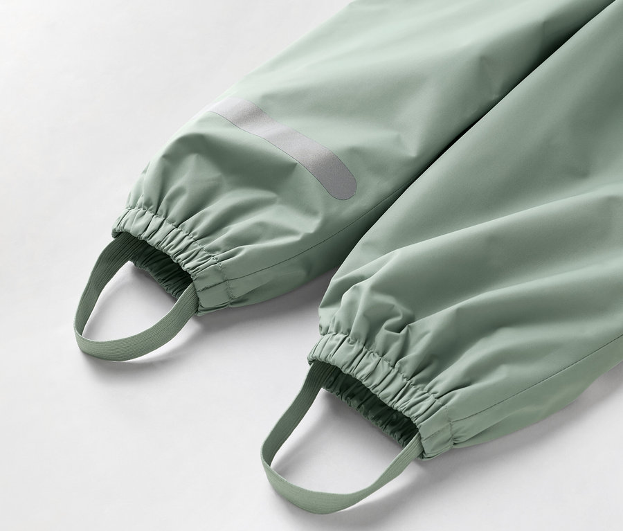 Közeli kép egy világoszöld nadrág aljáról, elasztikus mandzsettákkal és lábhurkokkal.