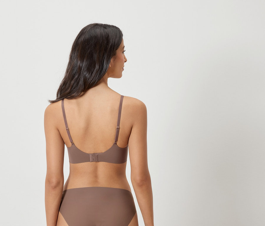 Hátulnézet egy sötét hajú nőről, aki barna melltartót és alsóneműt visel.