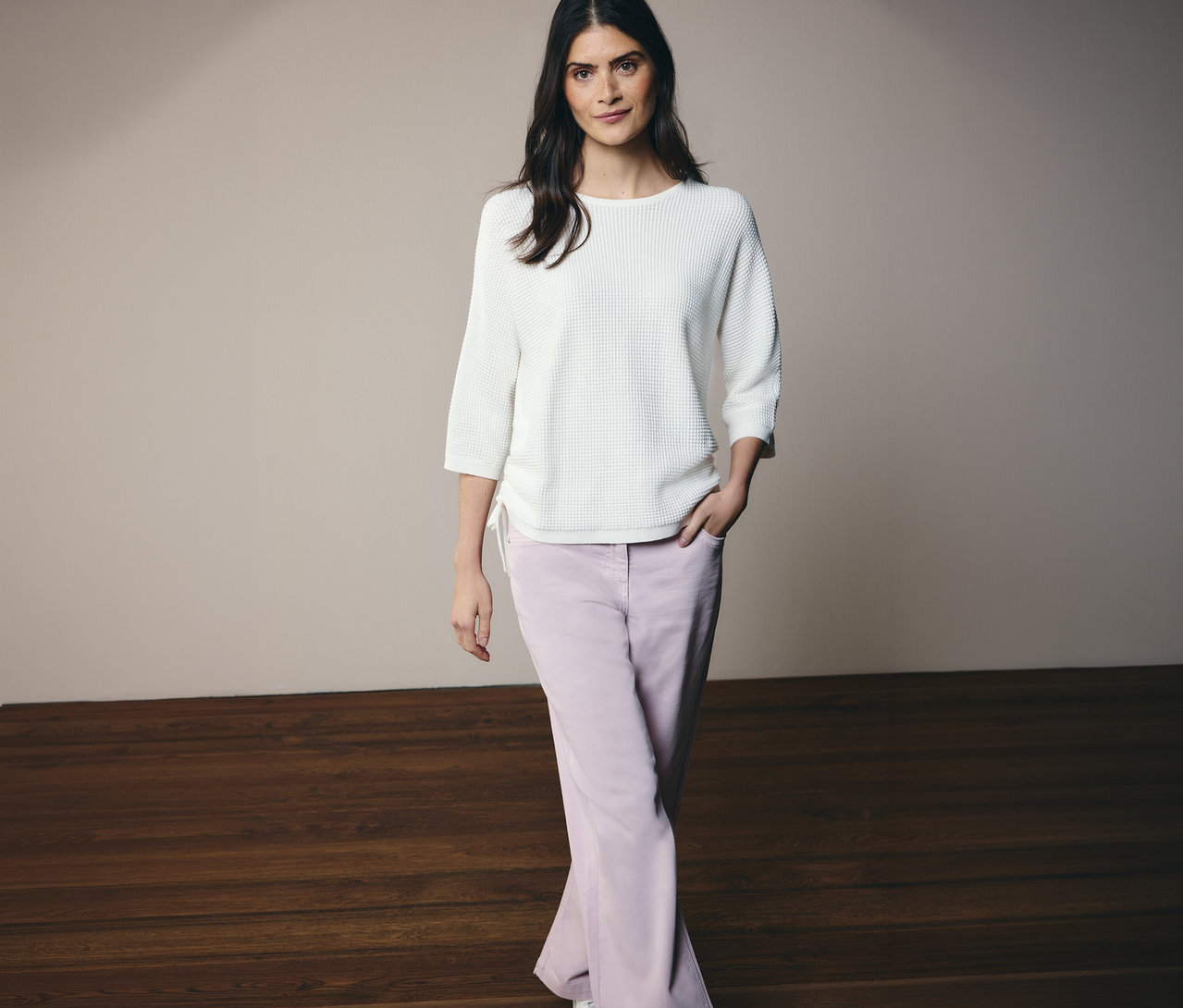 Nő pózol CECIL finomkötésű pulóverben és CECIL »Neele« farmernadrágban.