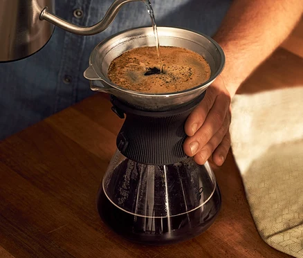Férfi vizet önt a BEEM Pour Over 0,75 l-es üvegkancsóba, kávészűrővel.