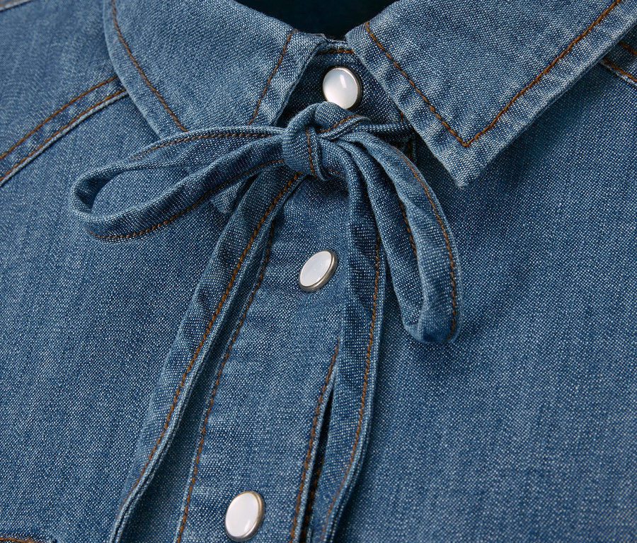 Kék, megkötős női farmerblúz részlete gombokkal.