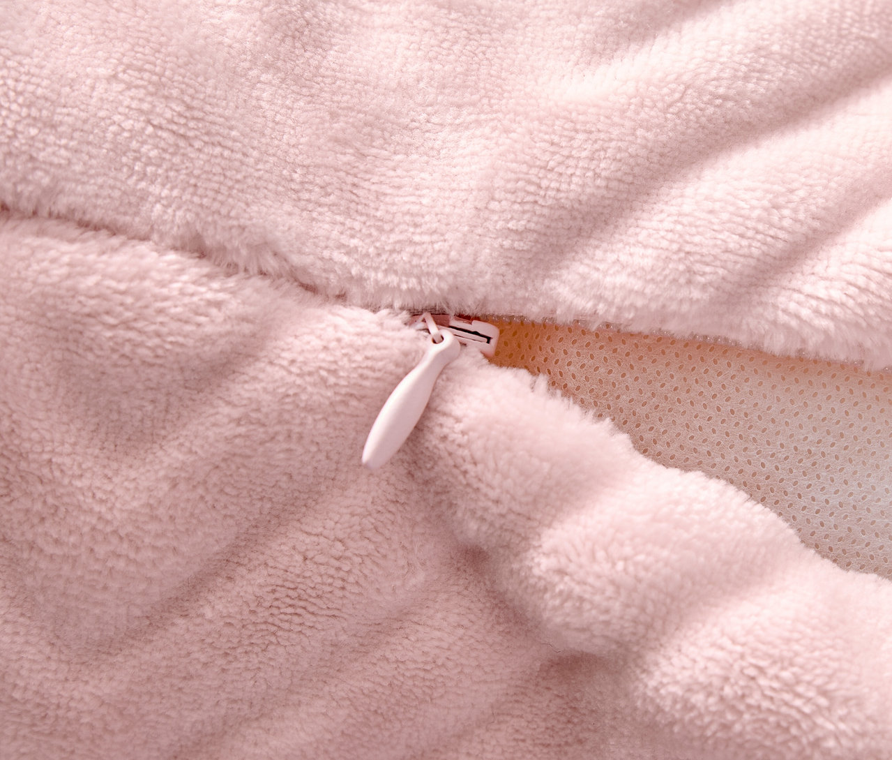 Egy rózsaszín párnahuzat részlete cipzárral.