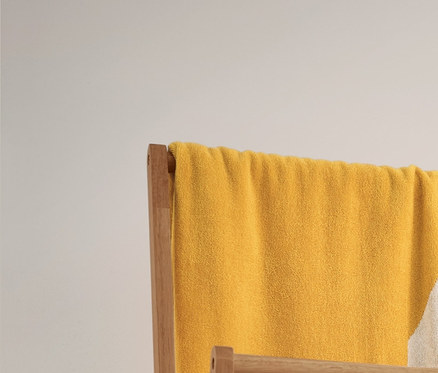 Egy sárga-fehér csíkos jacquard fürdőlepedő és 3 csíkos, bézs törölköző lóg egy összecsukható fa ruhaállványon. Alatta 2 fonott tárolókosár található.