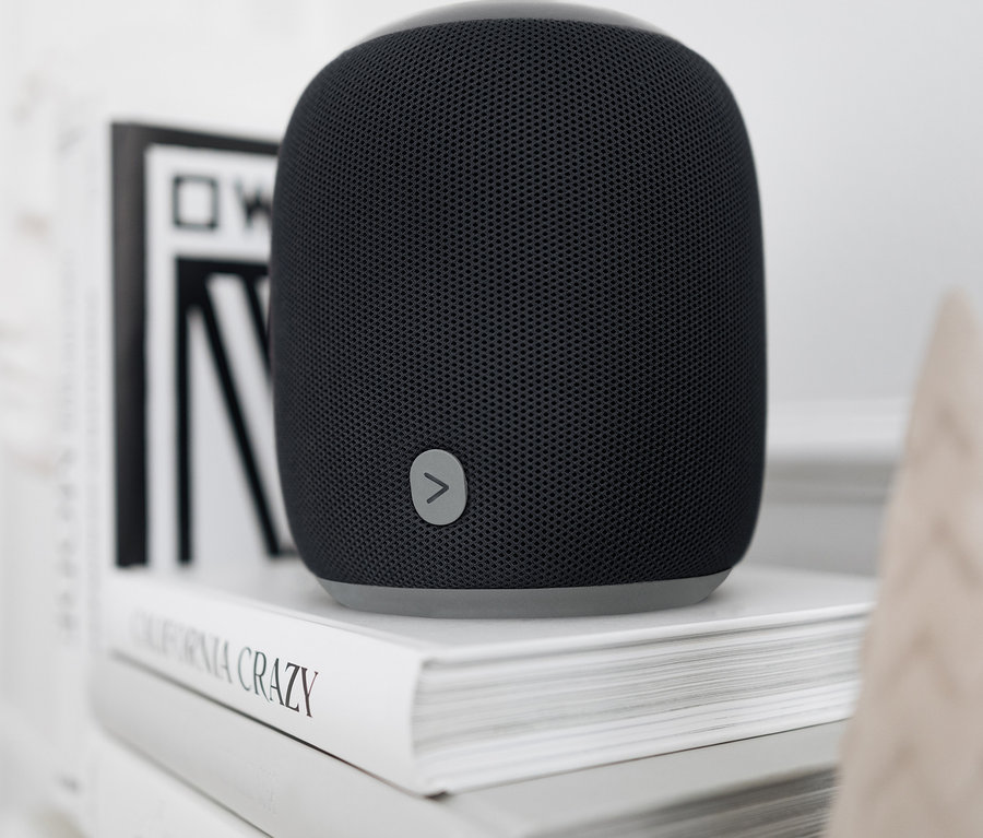 Egy fekete, nagy méretű Fabric Bluetooth® hangszóró áll két fehér könyvön.