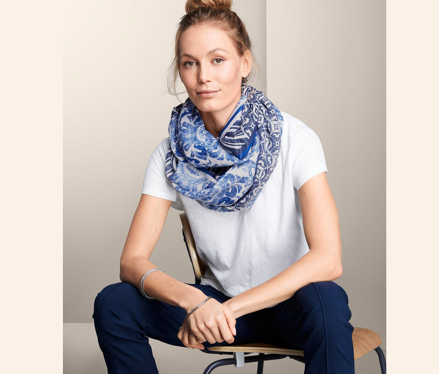 Nő ül, kék mintás csősálat visel.