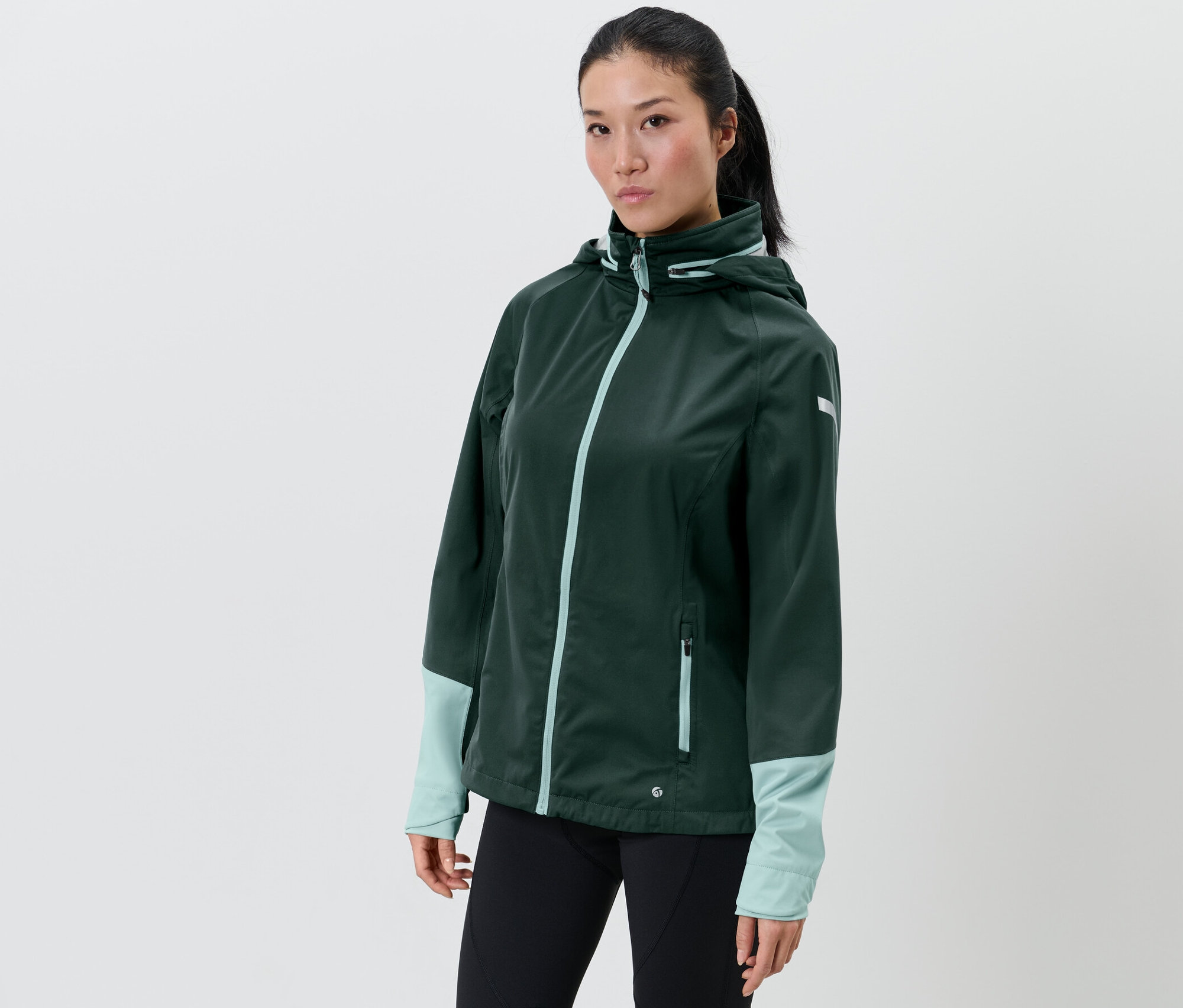Nő visel sötétzöld női kerékpáros esőkabátot.