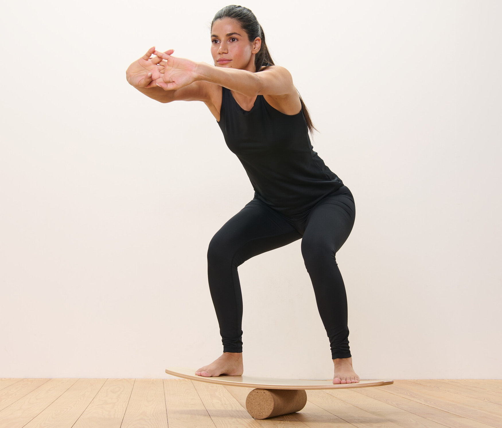 Nő guggolásokat végez egyensúlyozó deszkán.