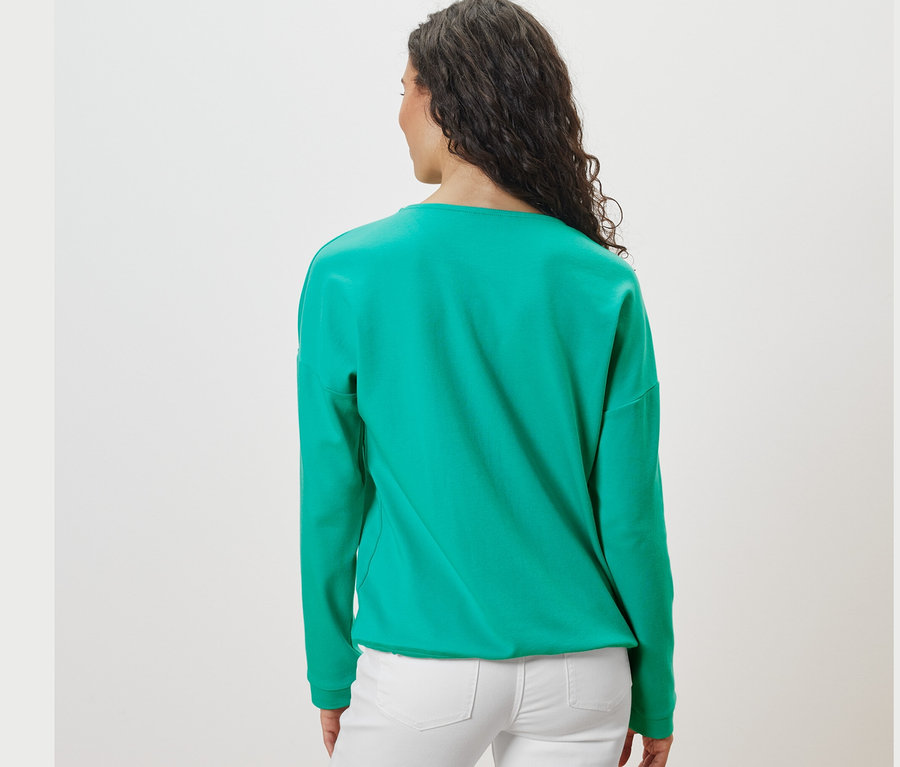 Hátulról látható egy sötét hajú nő türkiz szabadidőfelsőben.