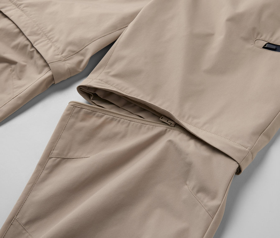 Egy bézs színű, 2 az 1-ben funkcionális nadrág részlete cipzárral.