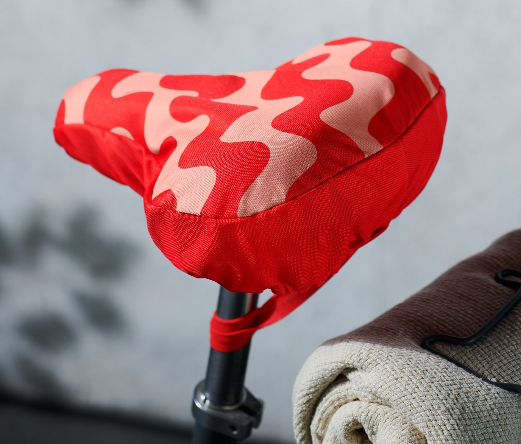 Egy kerékpár részlete, piros/rózsaszín mintás kerékpáros nyereghuzattal.