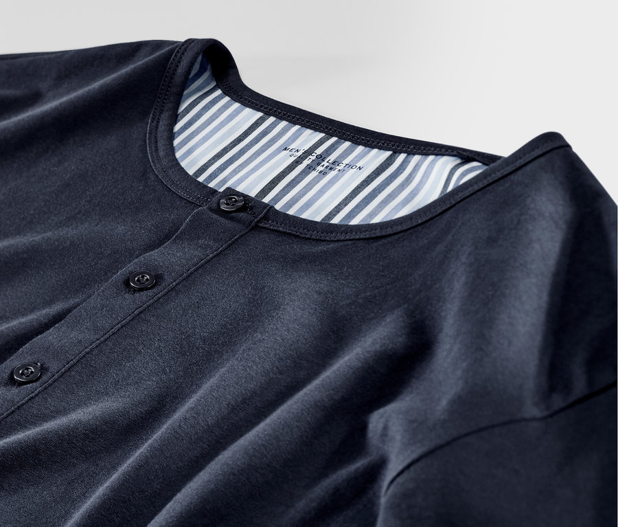 Közelkép egy szövött nadrággal ellátott férfi pizsama felsőrészéről.