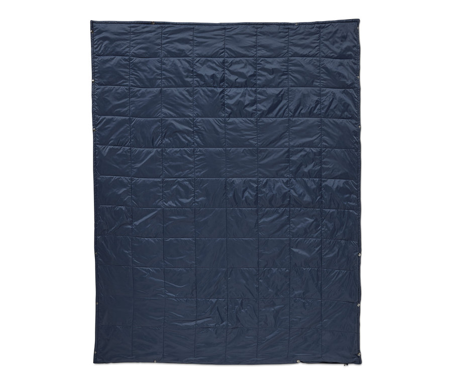 Egy sötétkék, steppelt, könnyű takaró utazáshoz.