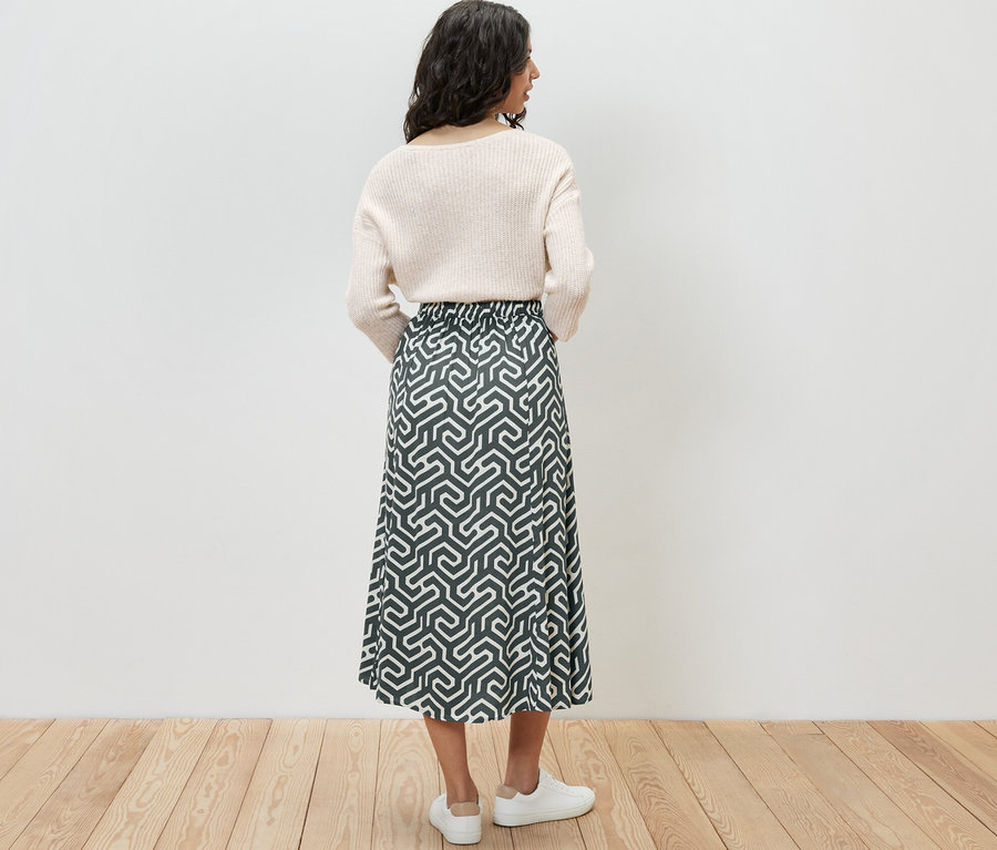 Hátulnézetű nő nyomott mintás midi szoknyában.