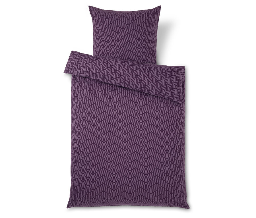 Lila ágynemű szett geometrikus mintával és párnával fehér háttérrel.