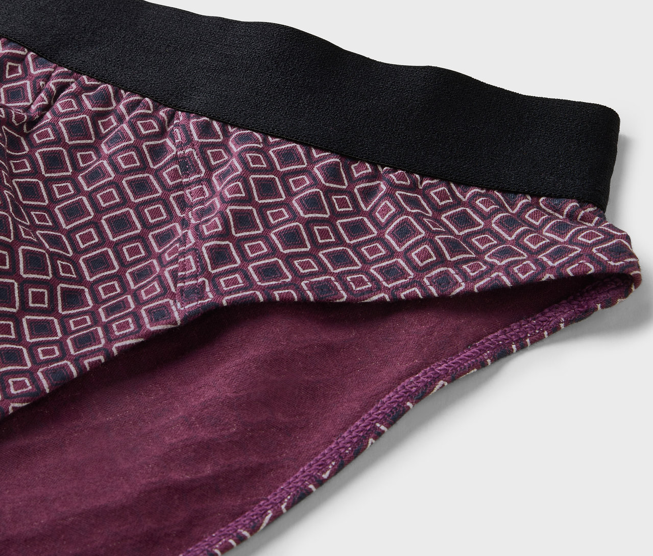 Egy lila, geometrikus mintás, fekete gumis derekú 4 darabos alsó részletfotója.