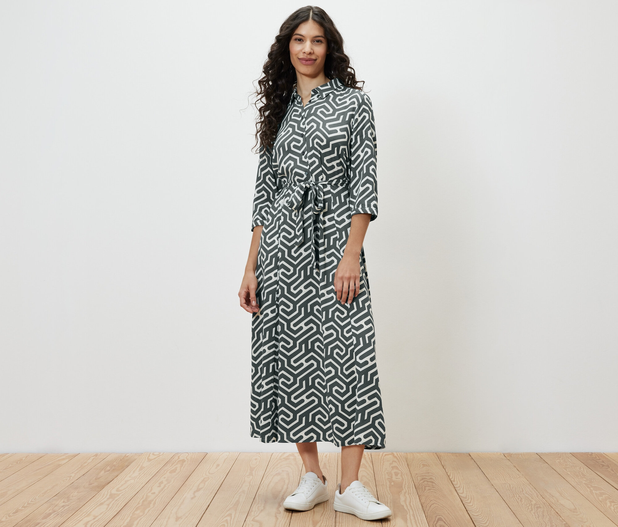 Egy nő áll nyomott mintás ingruhában.