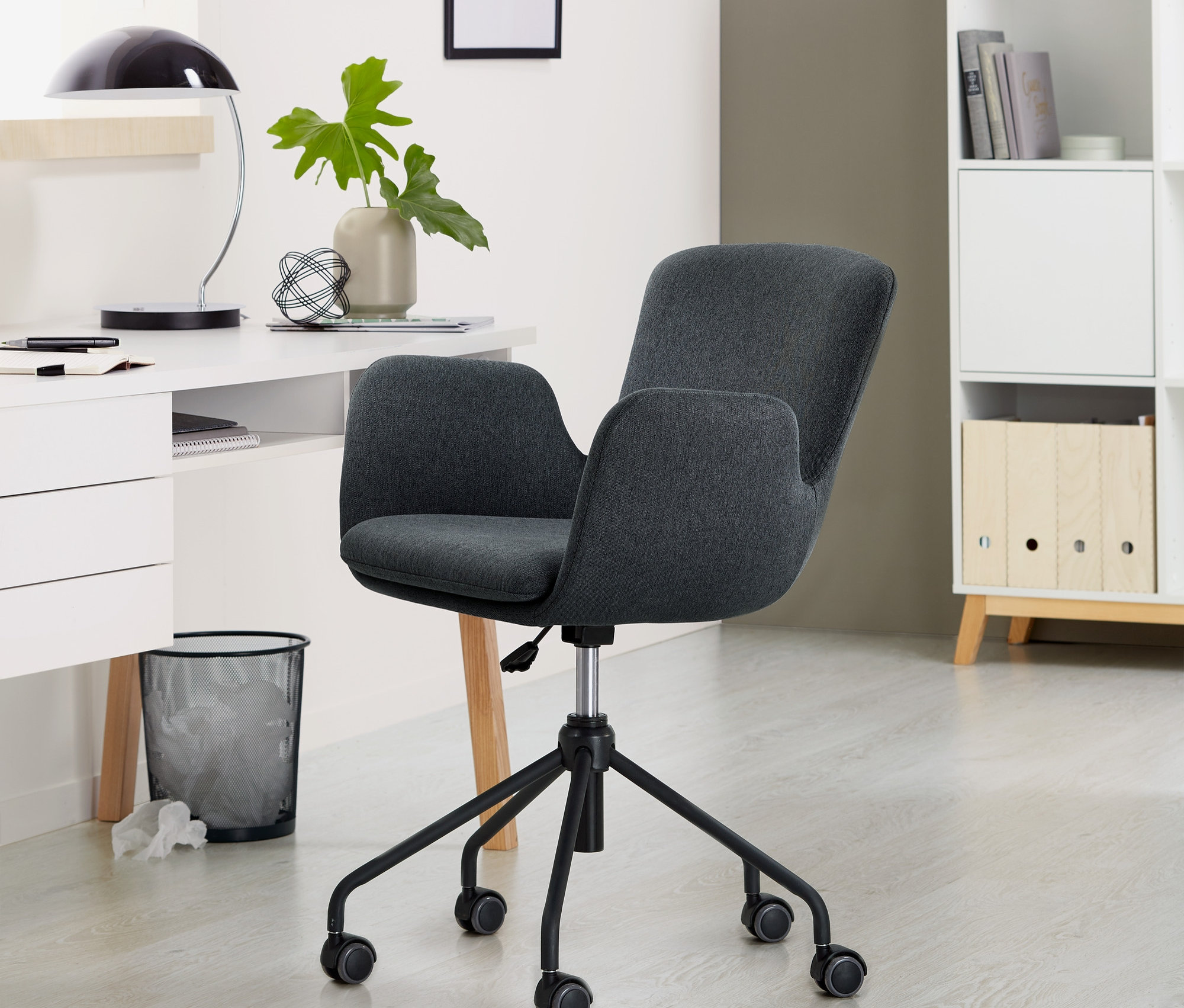 Egy antracit színű íróasztal szék áll a szobában.