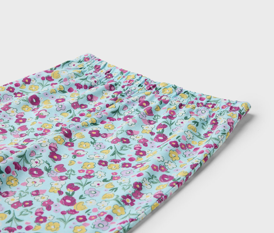 Egy világoskék, virágmintás, gumis derekú nadrág részlete.