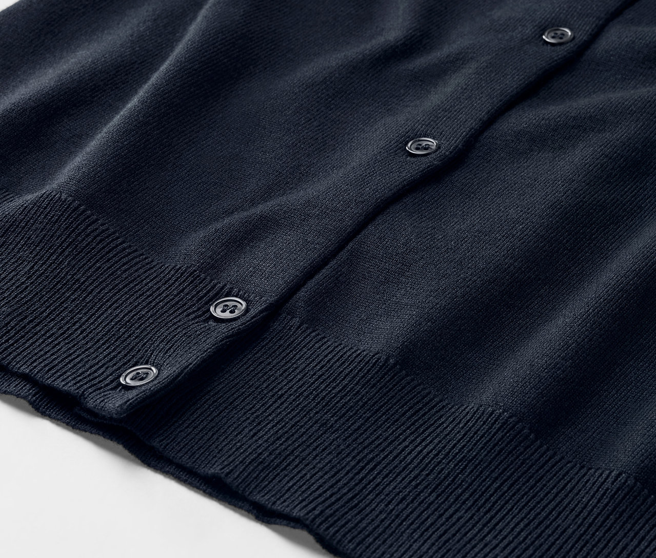 Kék, finomkötött kardigán részlete gombokkal.