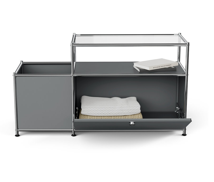 Szürke szekrény nyitott fiókkal, fehér takaróval és könyvvel a tetején.