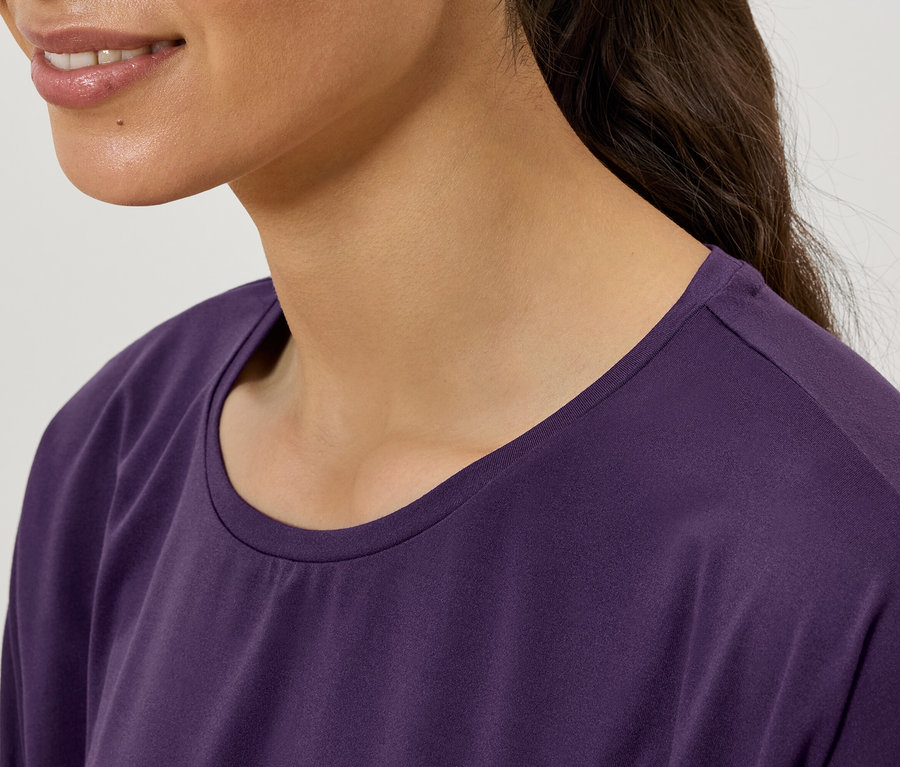 Egy nő részlete látható lila, kerek nyakú pólóban.