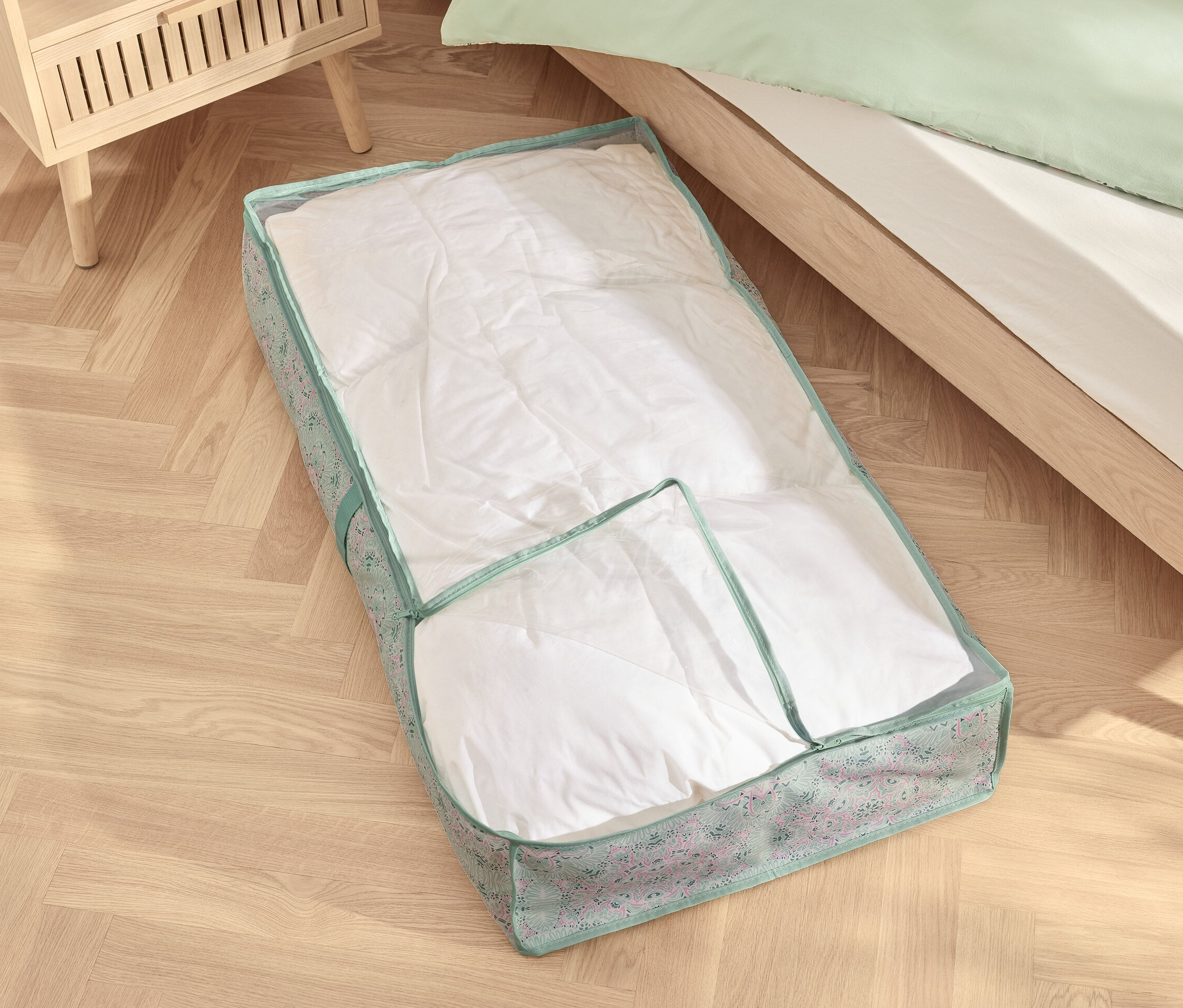 Egy ágy alatti komód fehér paplannal az ágy alatt.