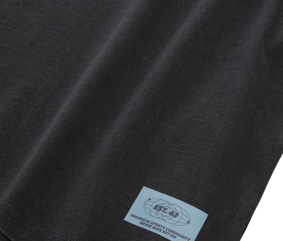 Egy fekete anyag közeli képe, világoskék címkével, melyen a következő felirat olvasható: "EST. 62 BROOKLYN SPORTS COMMUNITY NEVER BEEN BETTER".