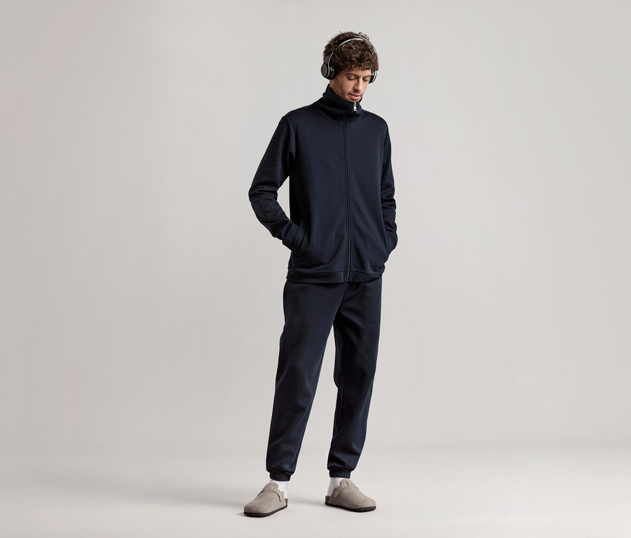 Férfi fejhallgatóval, sötétkék férfi szabadidő szettben.