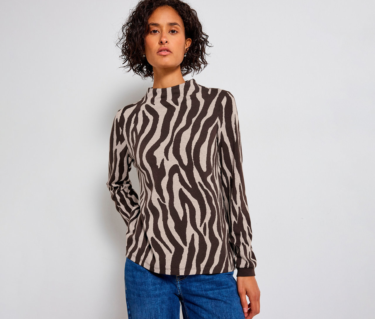 Nő visel egy zebra mintás Street One jacquard pólót és kék farmert.
